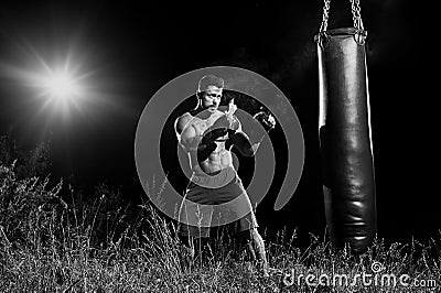 Professional boxer punching sandbag outdoors with his boxing glo Stock Photo