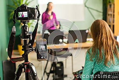 Professional camera is recording seminar with optional accessory. Woman making presentation, lection or meeting. Stock Photo