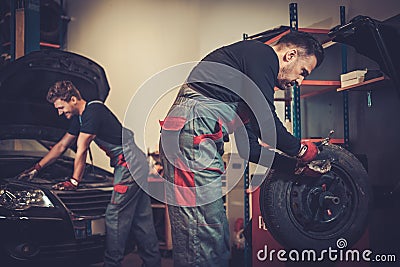 Professional car mechanic balancing car wheel on balancer in auto repair service. Stock Photo
