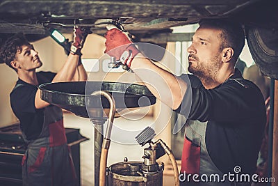 Professional car mechanic changing motor oil in automobile engi Stock Photo