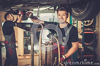 Professional car mechanic changing motor oil in automobile engine at maintenance repair service station in a car workshop. Stock Photo