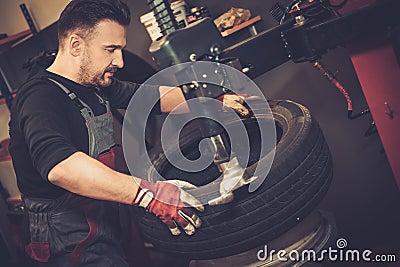 Professional car mechanic replace tire on wheel in auto repair Stock Photo