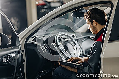 Mechanic Examining Car Engine With Help Of Laptop Stock Photo