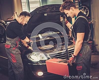 Professional car mechanics inspecting headlight lamp of automobile in auto repair Service. Stock Photo