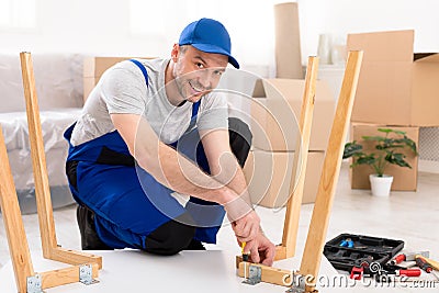 Professional Carpenter Assembling Table Sitting On Floor In Room Stock Photo