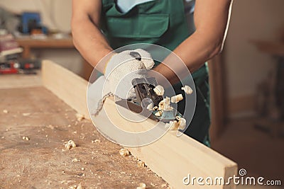 Professional carpenter grinding plank with jack plane in workshop, closeup Stock Photo