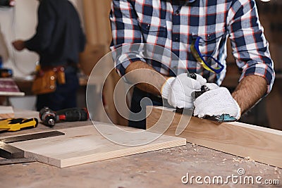 Professional carpenter grinding plank with jack plane in workshop, closeup Stock Photo