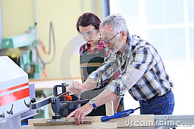 Professional carpenter teaching young woman apprentice Stock Photo