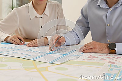 Professional cartographers working with cadastral map at table in office, closeup Stock Photo