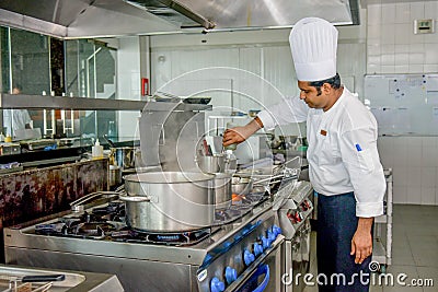 Professional chef adding ingredients to the dish while cooking Editorial Stock Photo