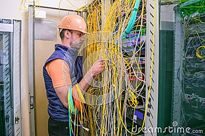 Professional communications guy unravels the wires in the data center server room. The specialist restores the Internet connection Stock Photo