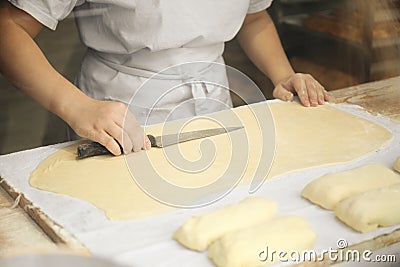 Professional cook cuts dough for baking in a small bakery Stock Photo