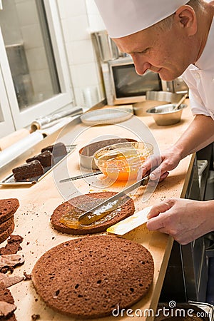 Professional cook spreading jam on cake Stock Photo