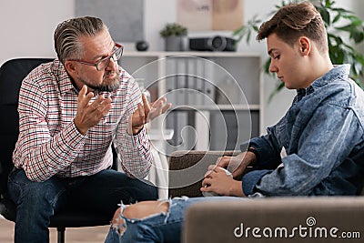 Professional counselor and troubled teenager during therapy meeting Stock Photo