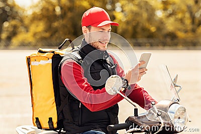 Professional Courier Using Smartphone Application Delivering Meals On Scooter Outside Stock Photo