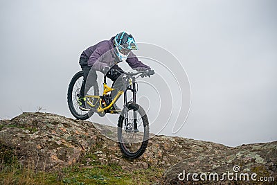 Professional Cyclist Riding Mountain Bike Down the Rocky Hill. Extreme Sport and Enduro Biking Concept. Stock Photo