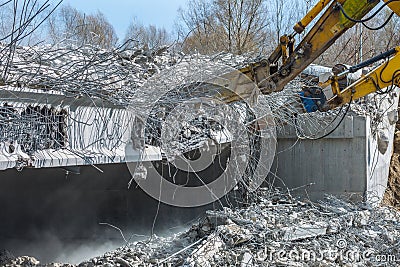 Professional demolition of reinforced concrete structures using industrial hydraulic hammer. Rods of metal fittings. Wreckage and Stock Photo