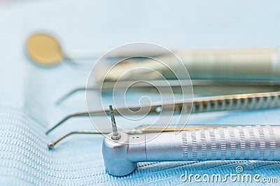 Professional dental tools on a doctor`s desk. Handpiece, tweezers and other tools on a blue background. Soft focus, shallow depth Stock Photo