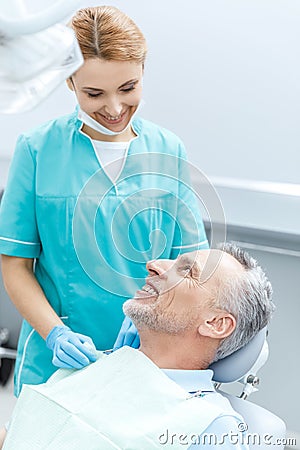 Professional dentist and mature patient looking at each other in dental office Stock Photo