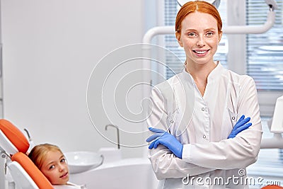 Professional Dentist Orthodontist Posing At Camera At Work Place, With Child Patient Stock Photo