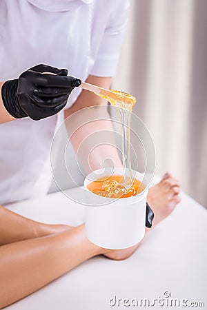 Professional depilation master removing unwanted hair from legs Stock Photo