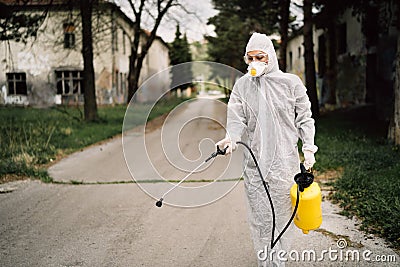 Professional disinfector in hazmat protection suit and N95 mask with chemical decontamination sprayer tank.Disinfecting streets Stock Photo