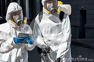 Professional disinfectors in protective hazmat suit walking through city streets Stock Photo