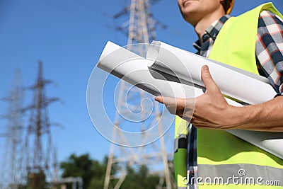 Professional electrician with draftings near high voltage tower, closeup Stock Photo