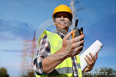 Electrician near high voltage tower, focus on hand with portable radio station Stock Photo