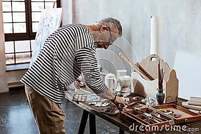 Professional experienced artist standing near the table with paints Stock Photo