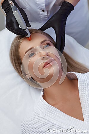 Professional female cosmetologist doing hydrafacial procedure in Cosmetology clinic. Stock Photo