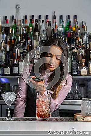 Professional female mixologist preparing cocktail in bar Stock Photo