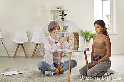 Professional female psychologist during therapy session disclosing teenage girl using jenga game. Stock Photo