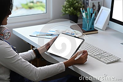 A professional female retoucher sitting at modern workspace and working with digital tablet. Stock Photo