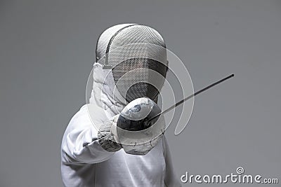 Professional fencer in fencing mask attacking on grey background Stock Photo
