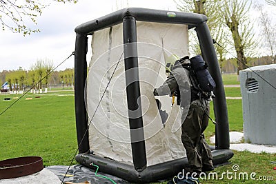A professional firefighter in a black special fireproof suit prepares to assemble a white oxygen tent to rescue people at a chemic Editorial Stock Photo