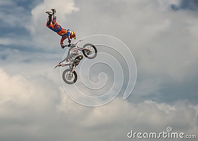 Professional Freestyle Motocross rider carries out a trick with the motorcycle on background of the blue cloud sky. German-Stuntda Editorial Stock Photo