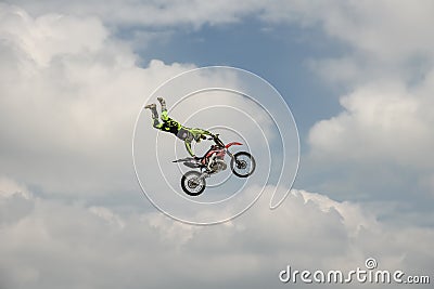 Professional Freestyle rider carries out a trick with the motorcycle on background of the blue cloud sky. Extreme sport. German-St Editorial Stock Photo
