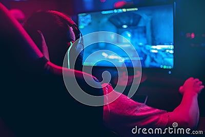 Professional gamer playing online games tournaments pc computer with headphones, Blurred red and blue background Stock Photo