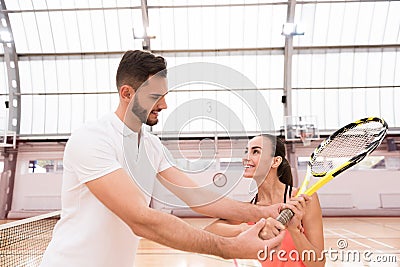 Professional handsome instructor showing woman how to play tennis Stock Photo
