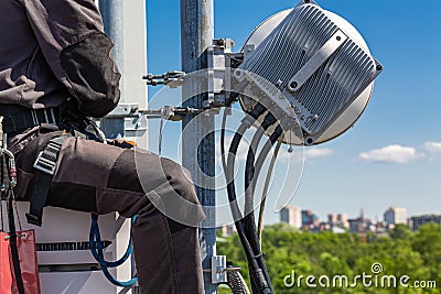Professional industrial climber in uniform and climber equipment on the telecommunication tower is installing outdoor Stock Photo