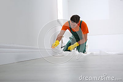 Professional janitor cleaning baseboard with brush after renovation Stock Photo