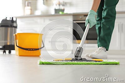 Professional janitor cleaning floor with mop in kitchen Stock Photo