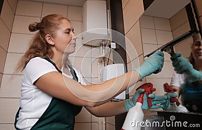 Professional janitor cleaning mirror with supplies Stock Photo