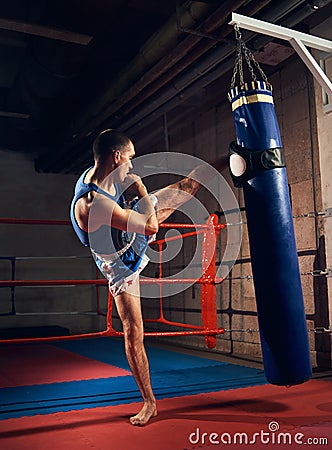 Handsome kick boxer training kicking and punching boxing bag Stock Photo