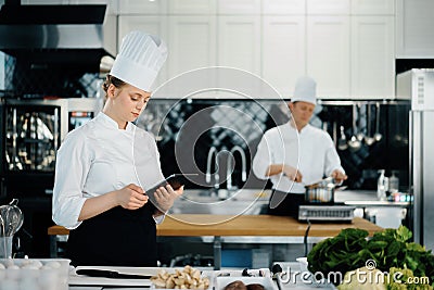 Professional kitchen of a restaurant, a female chef checks the availability of products from an employee. Restaurant warehouse Stock Photo