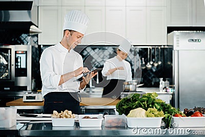 Professional kitchen of a restaurant, a male chef checks the availability of products from an employee. Restaurant warehouse Stock Photo