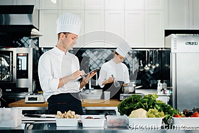 Professional kitchen of a restaurant, a male chef checks the availability of products from an employee. Restaurant warehouse Stock Photo