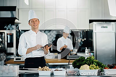 Professional kitchen of a restaurant, a male chef checks the availability of products from an employee. Restaurant warehouse Stock Photo