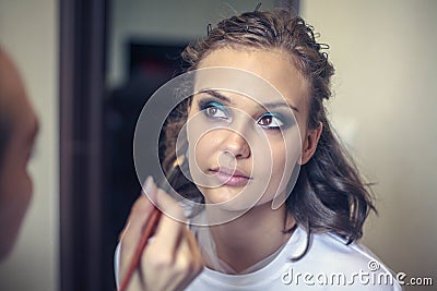 A professional makeup artist does make-up a beautiful young girl, tinted eyes, eyelashes and eyebrows Stock Photo